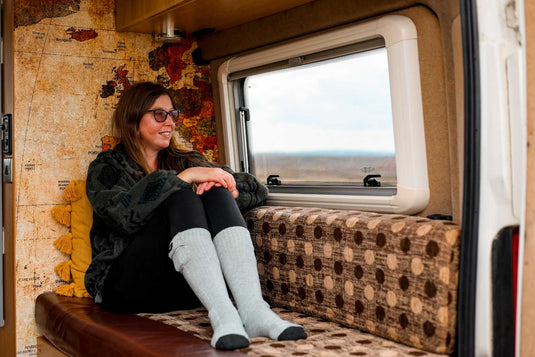 Woman sitting comfortably in a van wearing heated socks, enjoying a cozy winter experience.