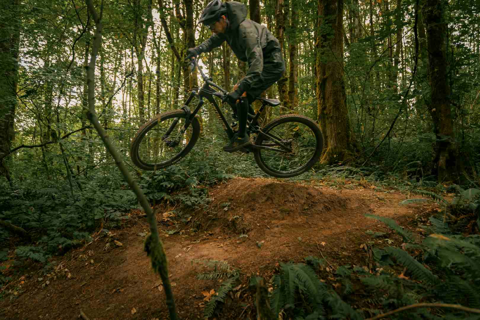 Cyclist jumping on a mountain bike in a forest trail during an off-road ride