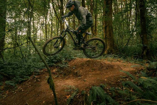 Cyclist jumping on a mountain bike in a forest trail during an off-road ride