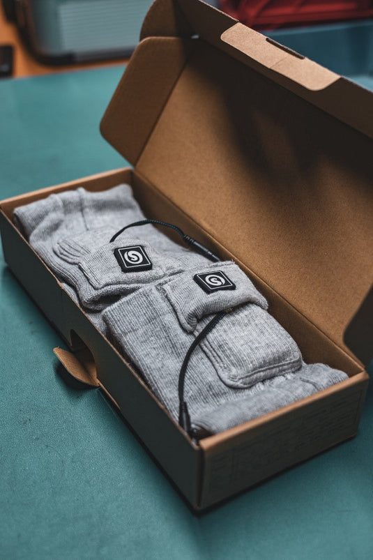 Pair of heated socks in a box, ready for use to keep feet warm during winter activities.