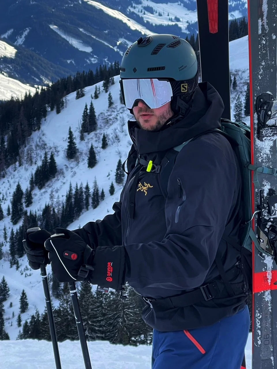 Skier wearing SAVIOR HEAT heated gloves while holding ski poles on the mountain