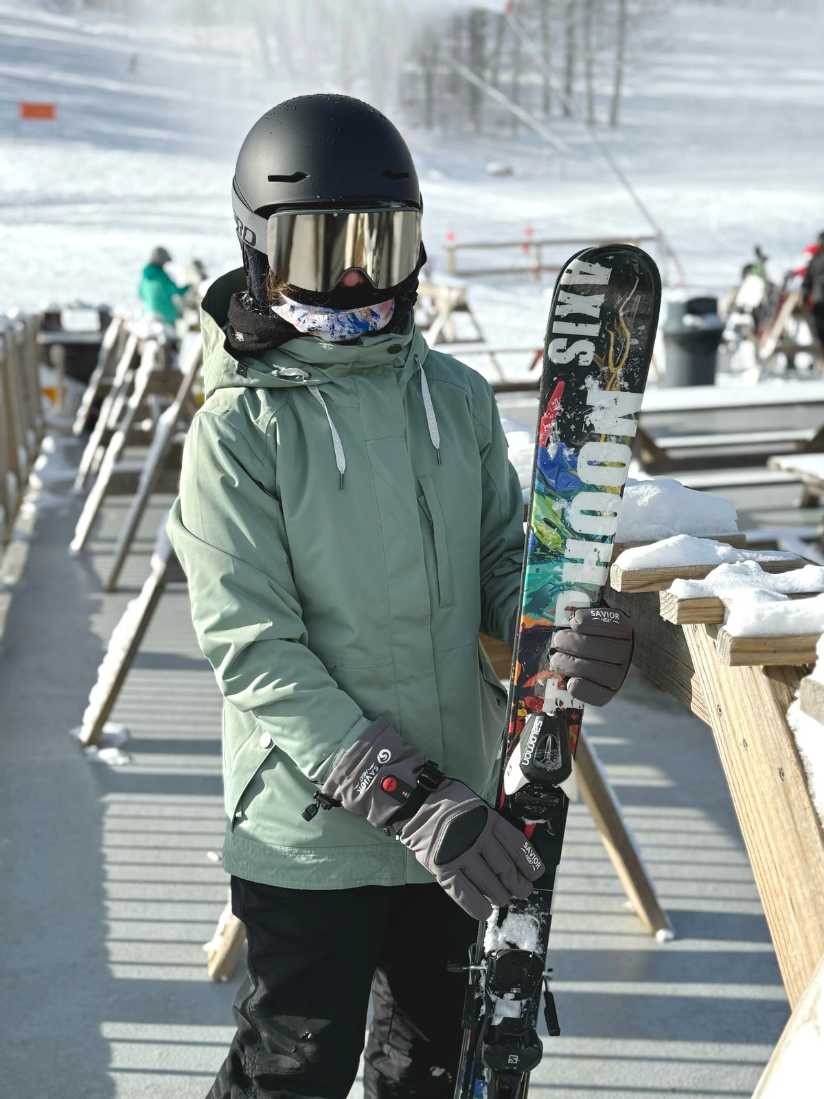 Snowboarder wearing SAVIOR HEAT heated gloves while carrying a board at the ski resort